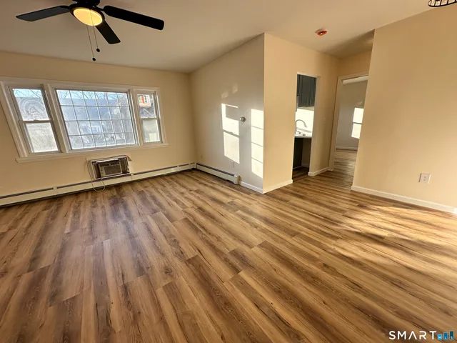 an empty room with wooden floor cabinet and windows