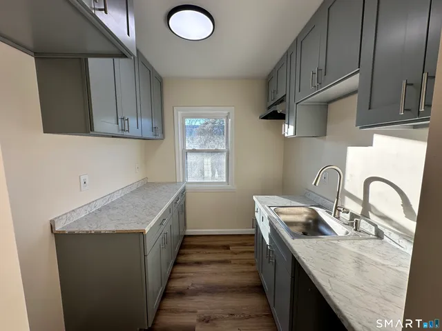 a kitchen with granite countertop a sink a stove and cabinets
