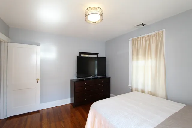a bedroom with a bed and a flat tv screen on dresser