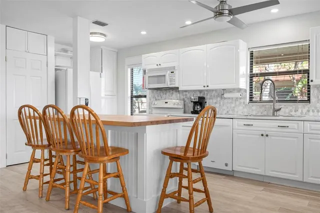a kitchen with stainless steel appliances granite countertop a dining table chairs and sink