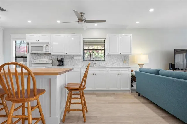 a kitchen with kitchen island a dining table chairs cabinets a sink and a window