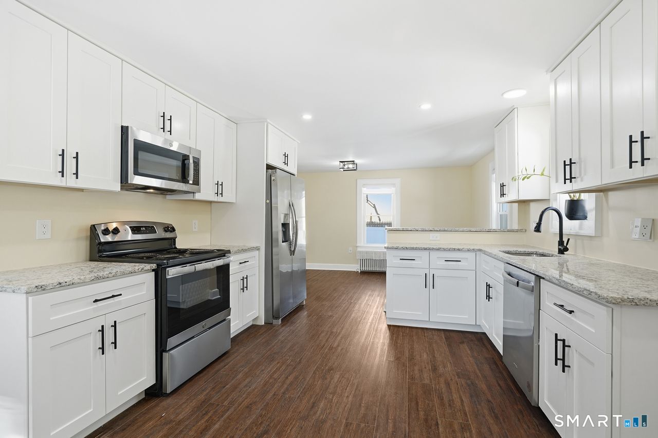 206 Gale Avenue Meriden, CT 06450 - Photo 11 of 33 a large kitchen with stainless steel appliances granite countertop a stove top oven a sink dishwasher and a refrigerator with wooden floor