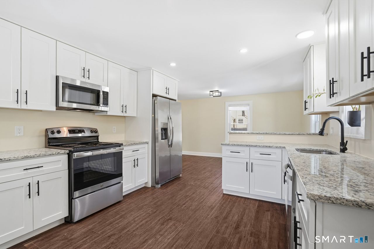 206 Gale Avenue Meriden, CT 06450 - Photo 12 of 33 a kitchen with stainless steel appliances granite countertop a stove a sink dishwasher a refrigerator and a microwave oven with wooden floor