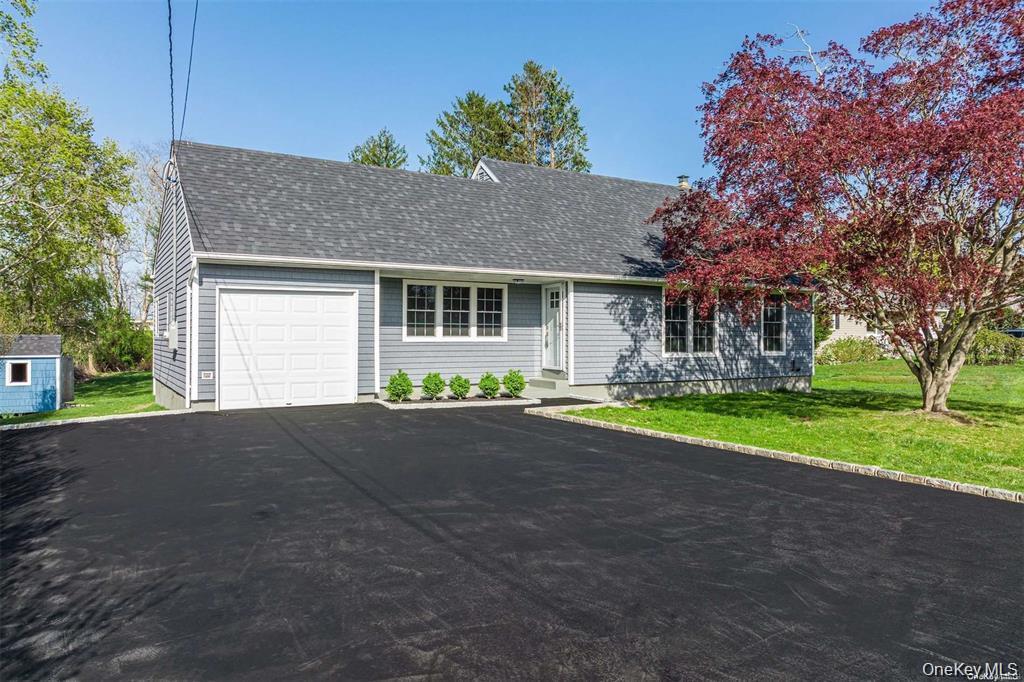 View of front of property with a front yard, roof with shingles, a garage, and asphalt driveway