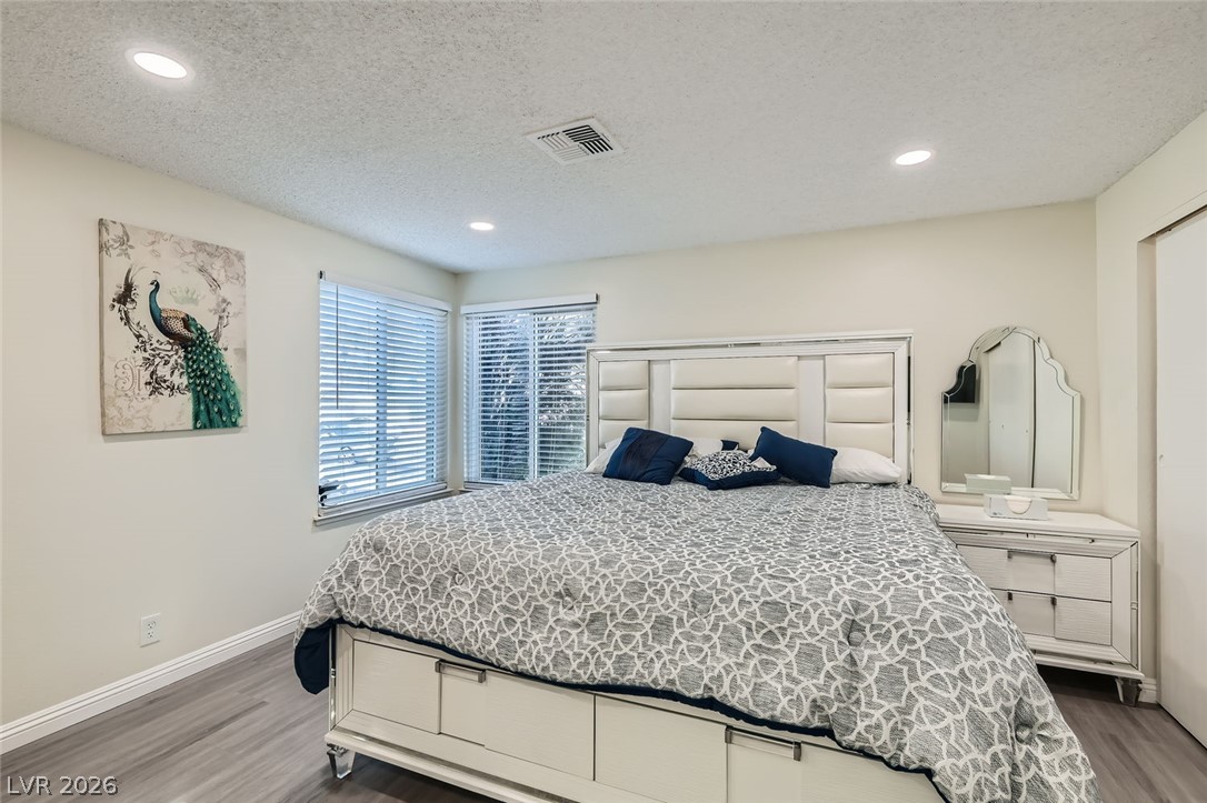 3665 Bronco Road Las Vegas, NV 89103 - Photo 14 of 28 Recessed lighting illuminates this inviting bedroom, featuring light-toned flooring and two windows.