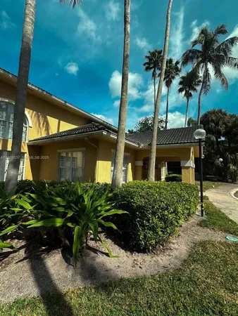 front view of a house with a yard and palm trees