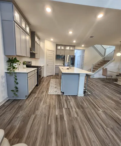 a living room with stainless steel appliances granite countertop furniture wooden floor and a view of kitchen