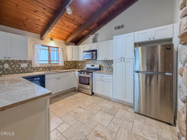 a kitchen with stainless steel appliances granite countertop a sink stove refrigerator and cabinets