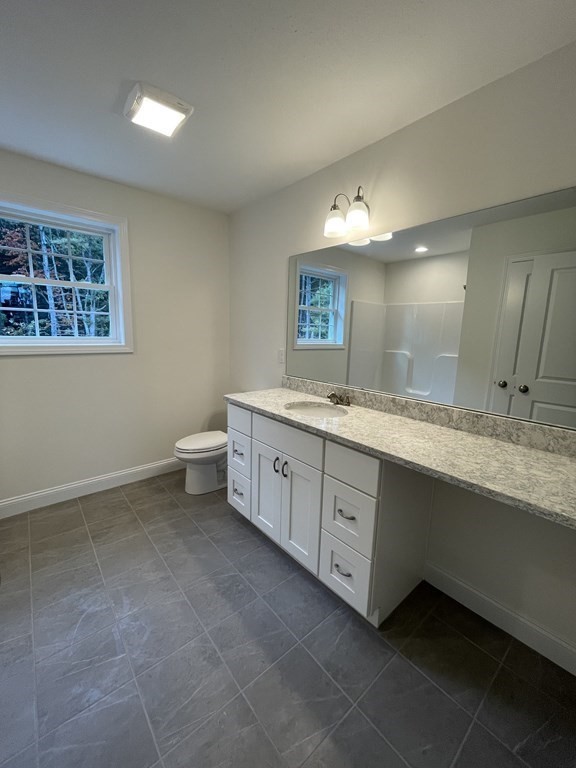 12 Hayfield Road, Unit 1 Dracut, MA 01826 - Photo 27 of 32 a spacious bathroom with a granite countertop sink a toilet and a mirror