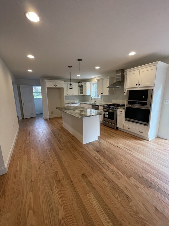 12 Hayfield Road, Unit 1 Dracut, MA 01826 - Photo 6 of 32 a kitchen with stainless steel appliances kitchen island granite countertop wooden floors and view living room