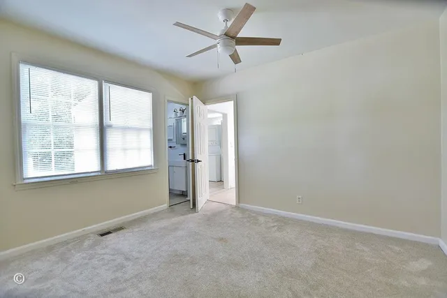 an empty room with a window and a fan