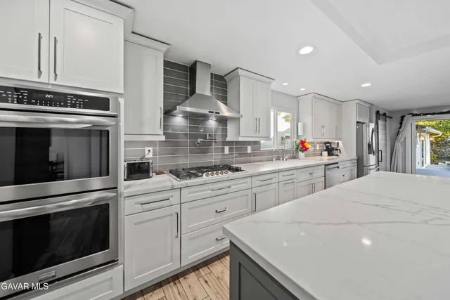 a kitchen with stainless steel appliances a stove a sink and white cabinets