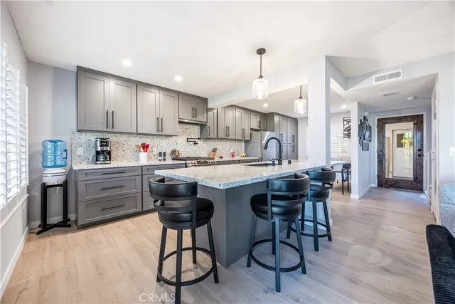 a kitchen with stainless steel appliances kitchen island granite countertop a table chairs sink and cabinets
