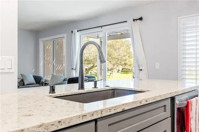 a view of a kitchen with granite countertop sink and natural light