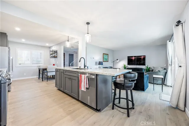 a kitchen with stainless steel appliances granite countertop a table chairs sink and cabinets