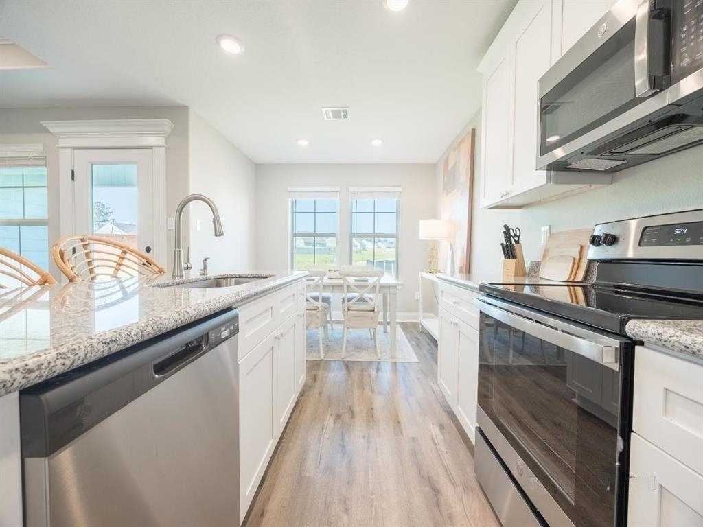 23906 Peppermint Street Elberta, AL 36530 - Photo 5 of 14 Kitchen with stainless steel appliances, white cabinetry, light wood-style flooring, light stone counters, and recessed lighting