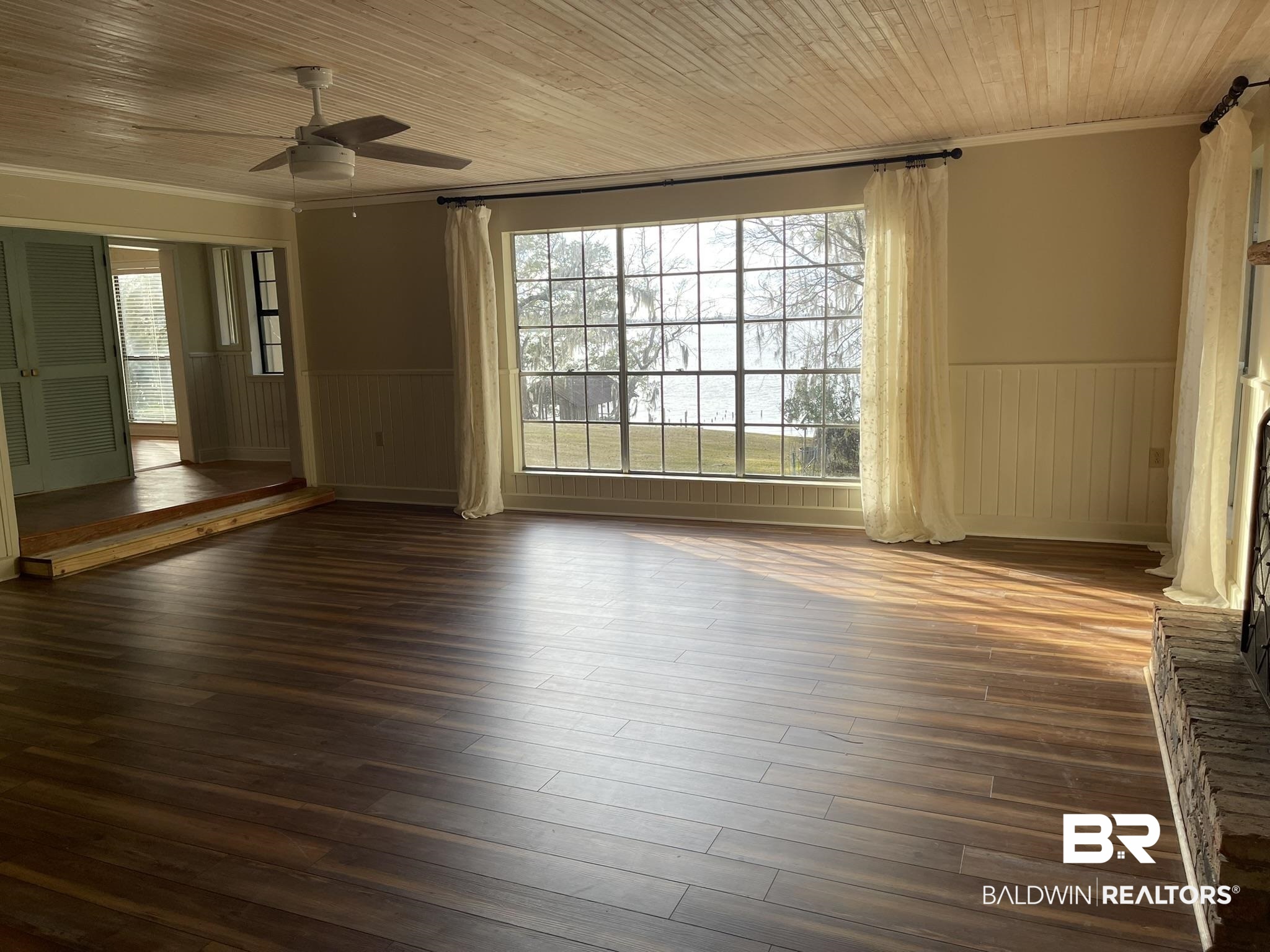 6621 Purvis Road Daphne, AL 36527 - Photo 25 of 59 Empty room with wood ceiling, a ceiling fan, ornamental molding, dark wood-type flooring, and wainscoting