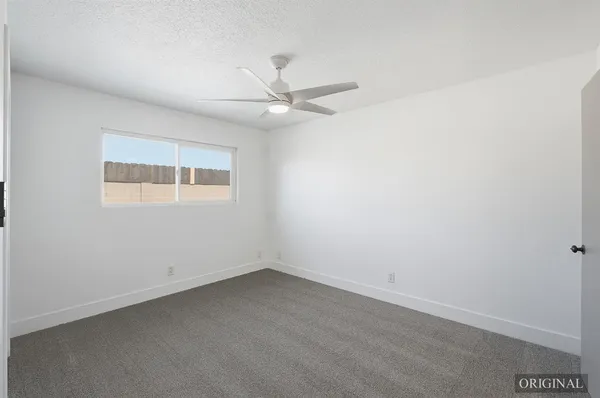 an empty room with a window and ceiling fan