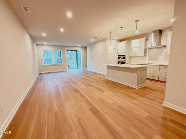 a large kitchen with kitchen island a sink wooden floor and white cabinets