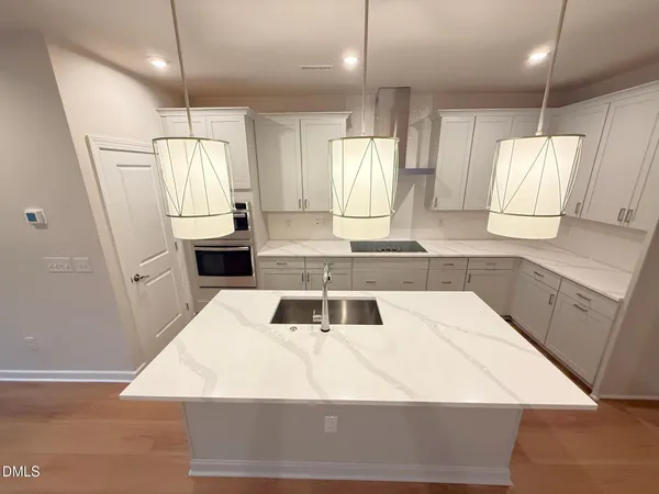 a large white kitchen with a stove a sink a refrigerator and a window