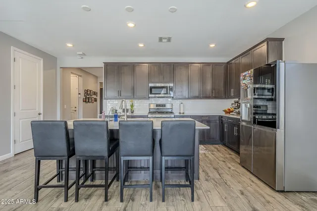 a kitchen with stainless steel appliances granite countertop a refrigerator a stove top oven a sink and cabinets