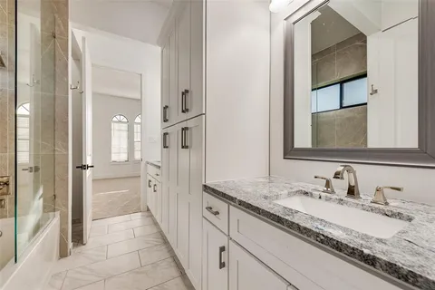 a en suite bathroom with a granite countertop sink and a mirror