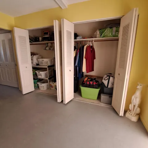 a view of walk in closet with clothes and shoes