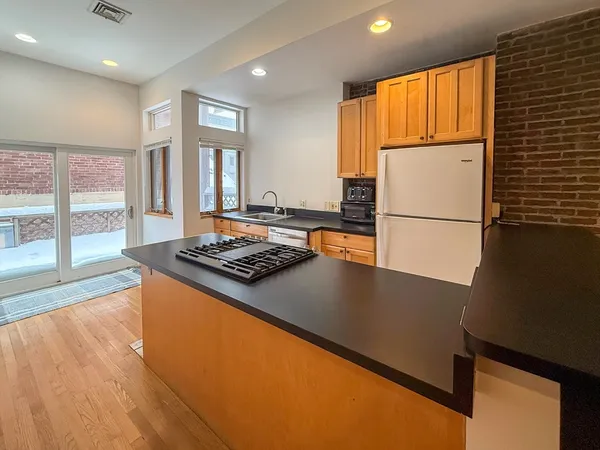 a view of a kitchen with a stove wooden cabinets and a refrigerator