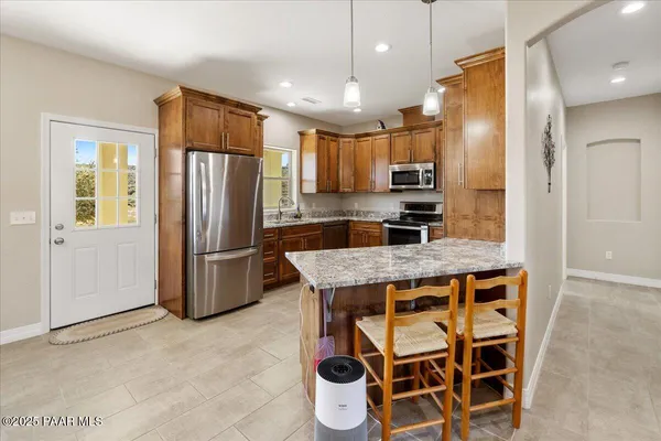 a kitchen with stainless steel appliances kitchen island granite countertop a refrigerator and microwave