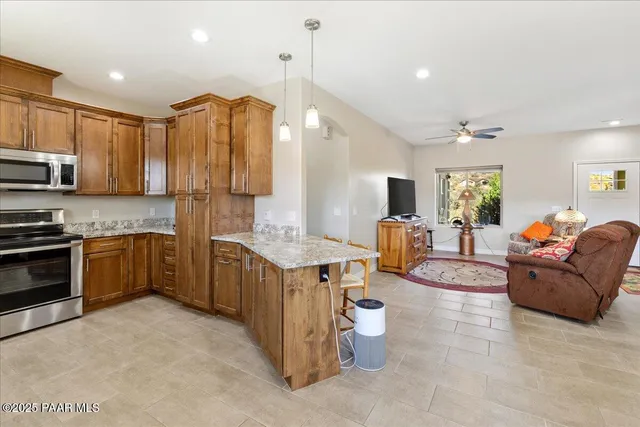 a living room with stainless steel appliances kitchen island granite countertop a refrigerator a stove a sink dishwasher and a microwave with wooden floor