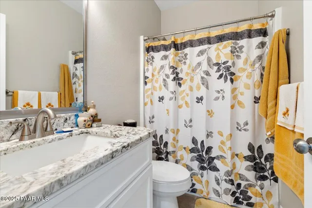 a bathroom with a granite countertop sink a toilet and a mirror