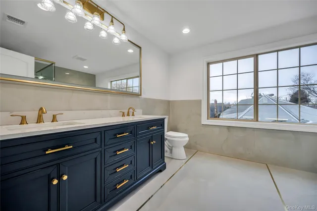 a spacious bathroom with a granite countertop sink a toilet and a window