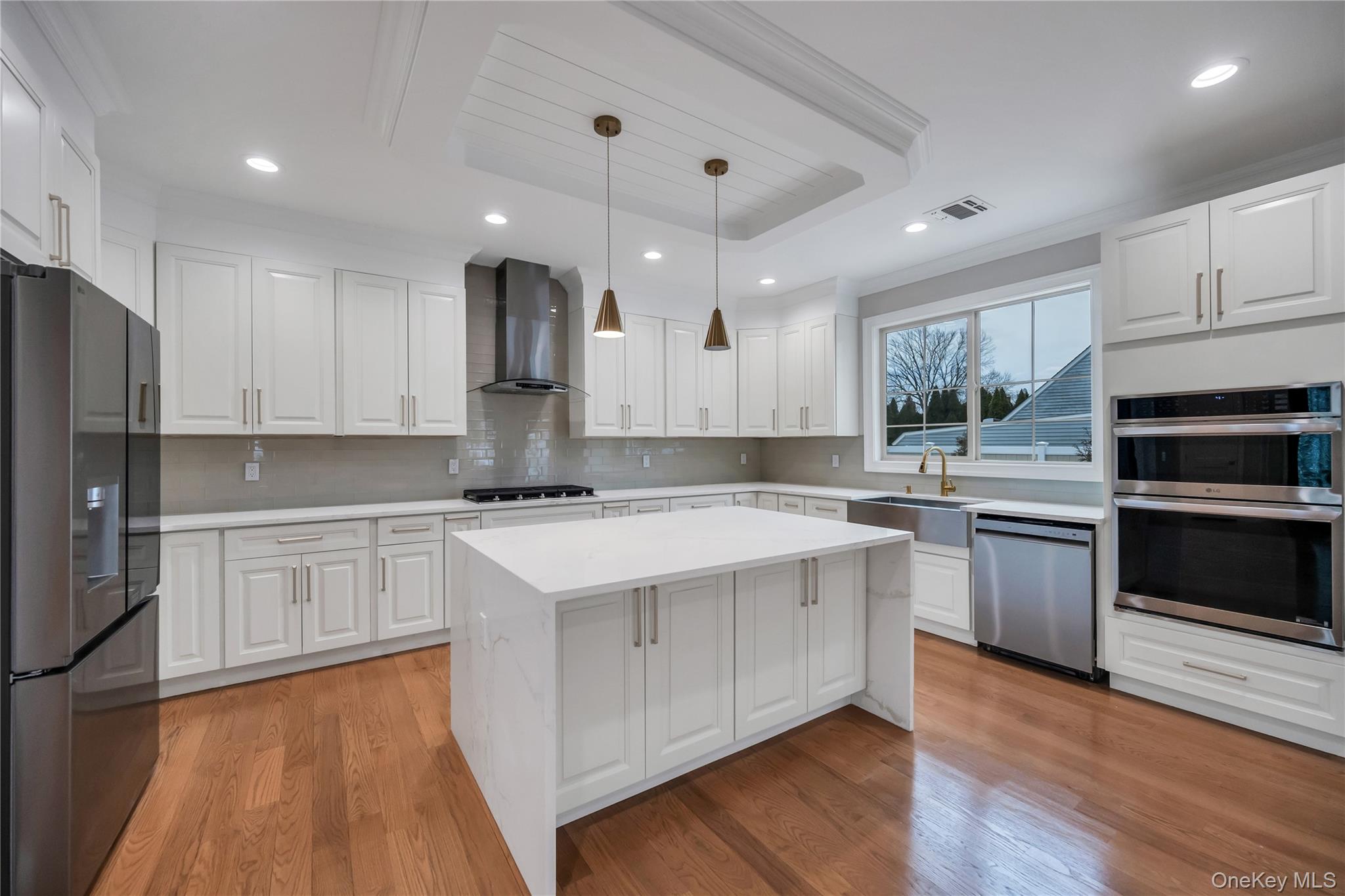 319 Blacksmith Road Levittown, NY 11756 - Photo 3 of 16 Kitchen with appliances with stainless steel finishes, wall chimney exhaust hood, a sink, light countertops, and tasteful backsplash