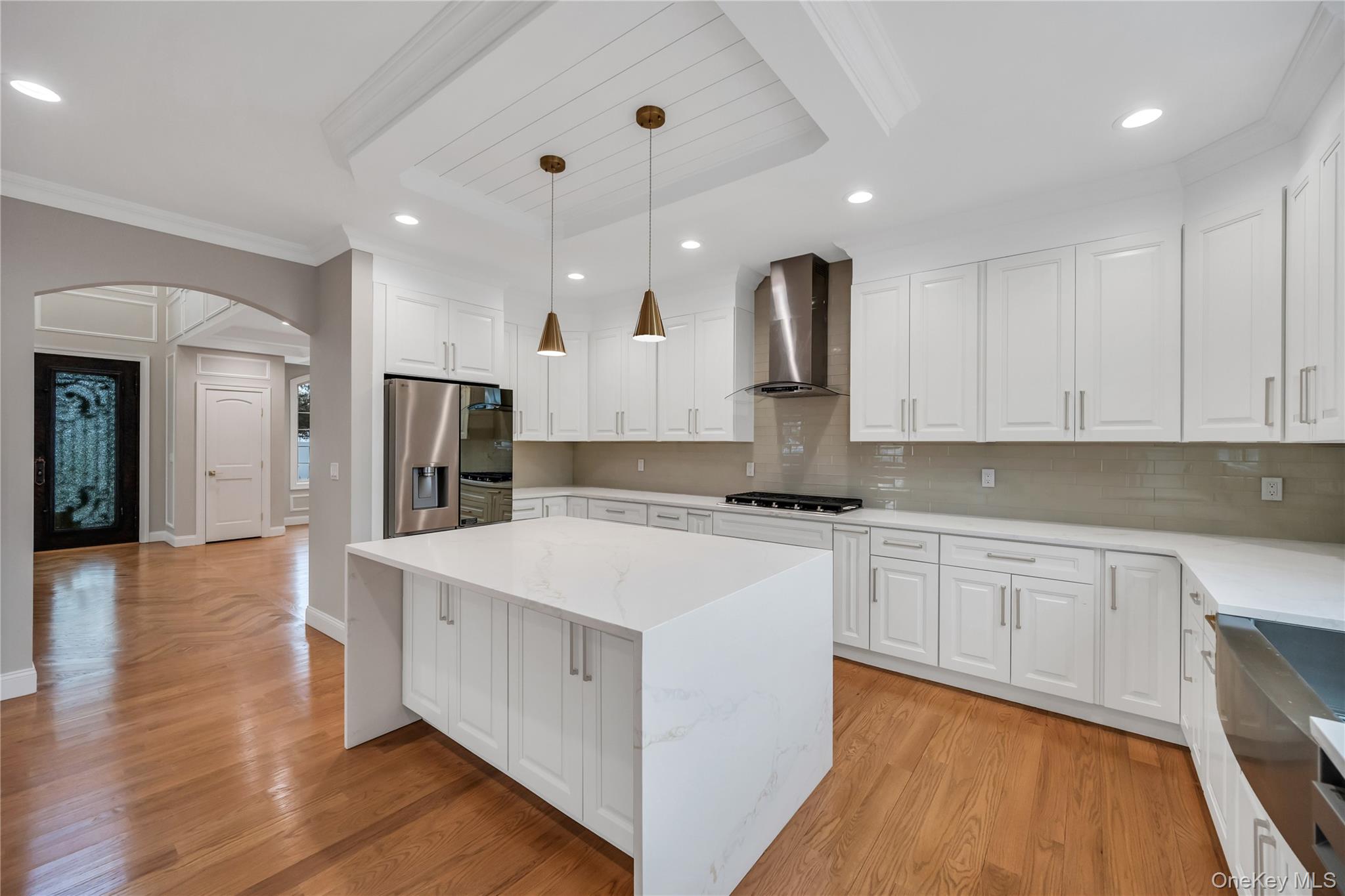 319 Blacksmith Road Levittown, NY 11756 - Photo 4 of 16 Kitchen featuring appliances with stainless steel finishes, wall chimney exhaust hood, arched walkways, crown molding, and decorative backsplash