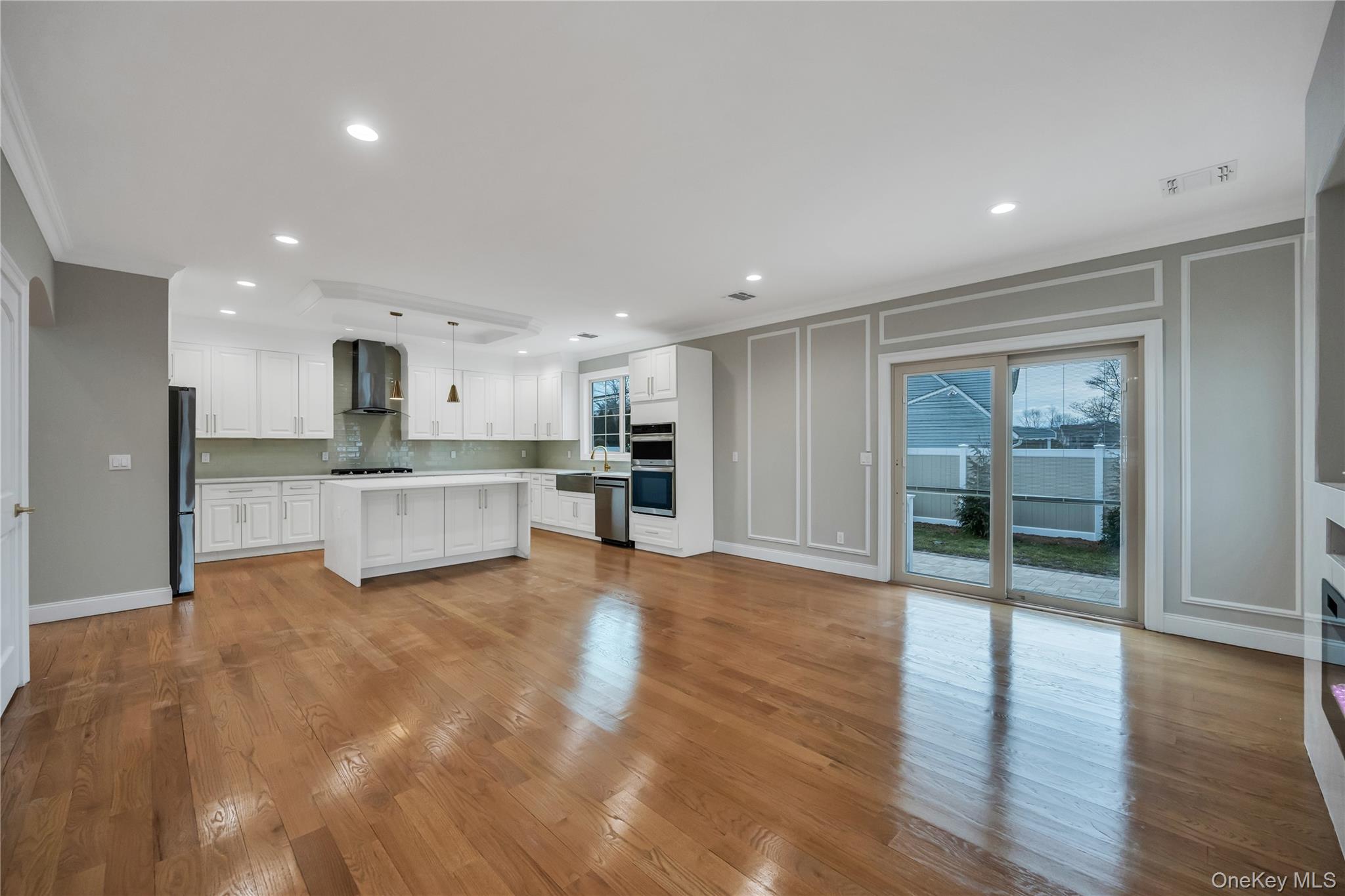319 Blacksmith Road Levittown, NY 11756 - Photo 8 of 16 Kitchen featuring a decorative wall, appliances with stainless steel finishes, wall chimney exhaust hood, crown molding, and light countertops