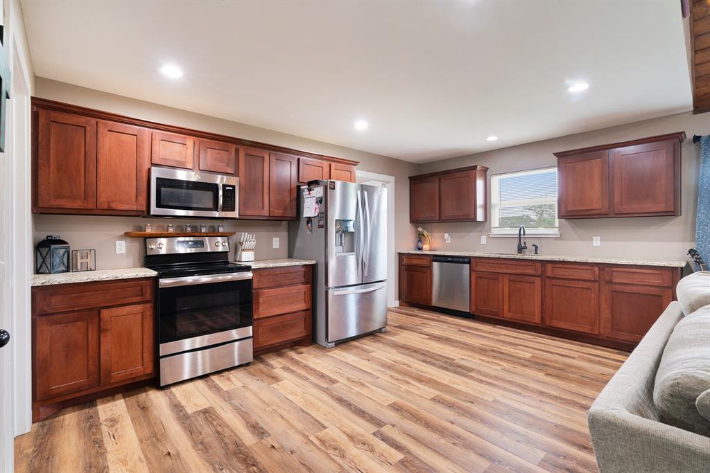134 Private Road Paris, TX 75462 - Photo 8 of 19 a kitchen with stainless steel appliances wooden cabinets a stove top oven a sink and dishwasher a refrigerator with wooden floor