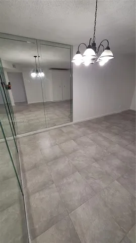 a view of an empty room with a chandelier fan