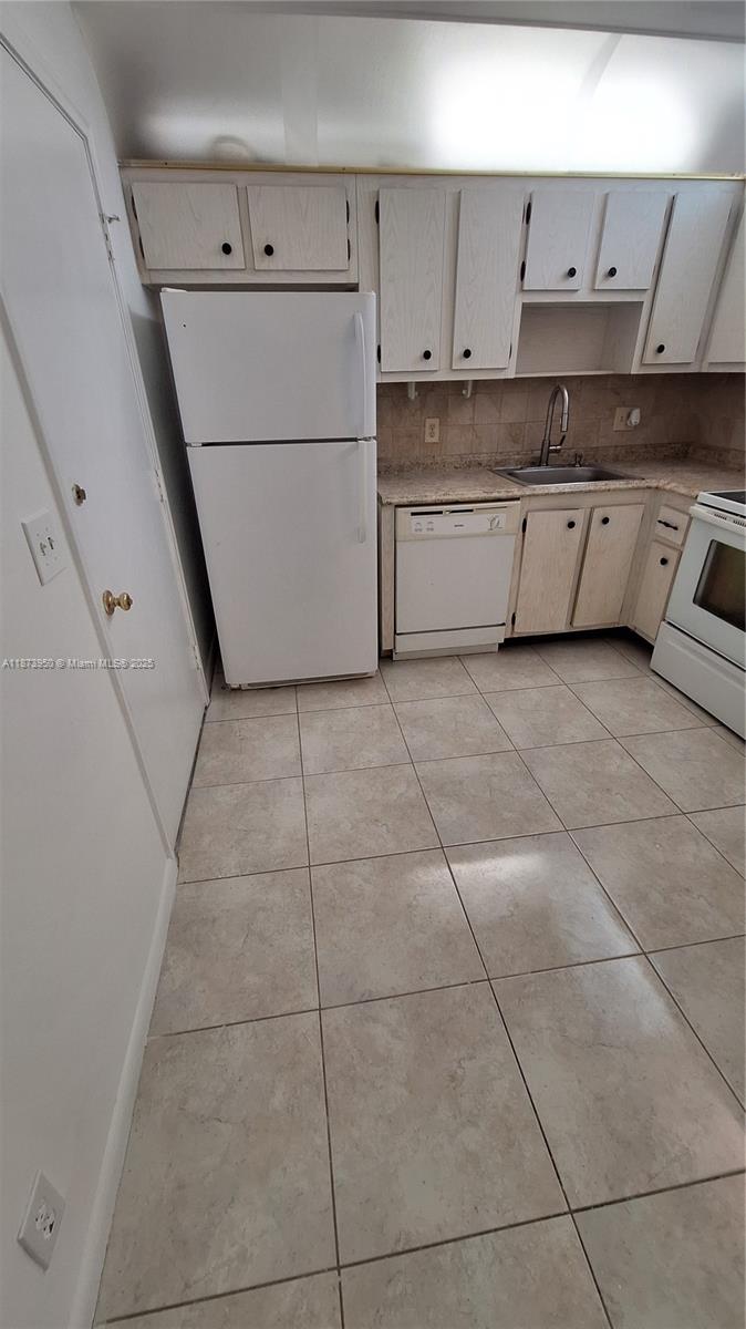 22605 Southwest 66th Avenue, Unit 409 Boca Raton, FL 33428 - Photo 5 of 19 a kitchen with granite countertop white cabinets and white appliances