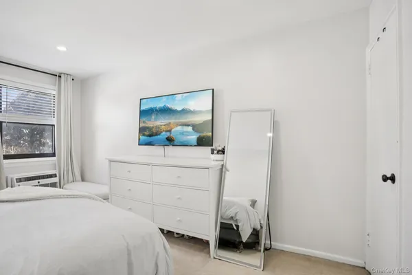 a bedroom with a bed and a flat tv screen on the dresser