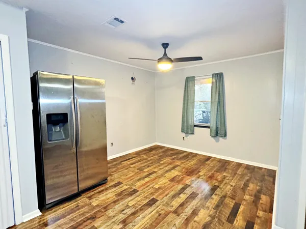 an empty room with wooden floor cabinet and windows
