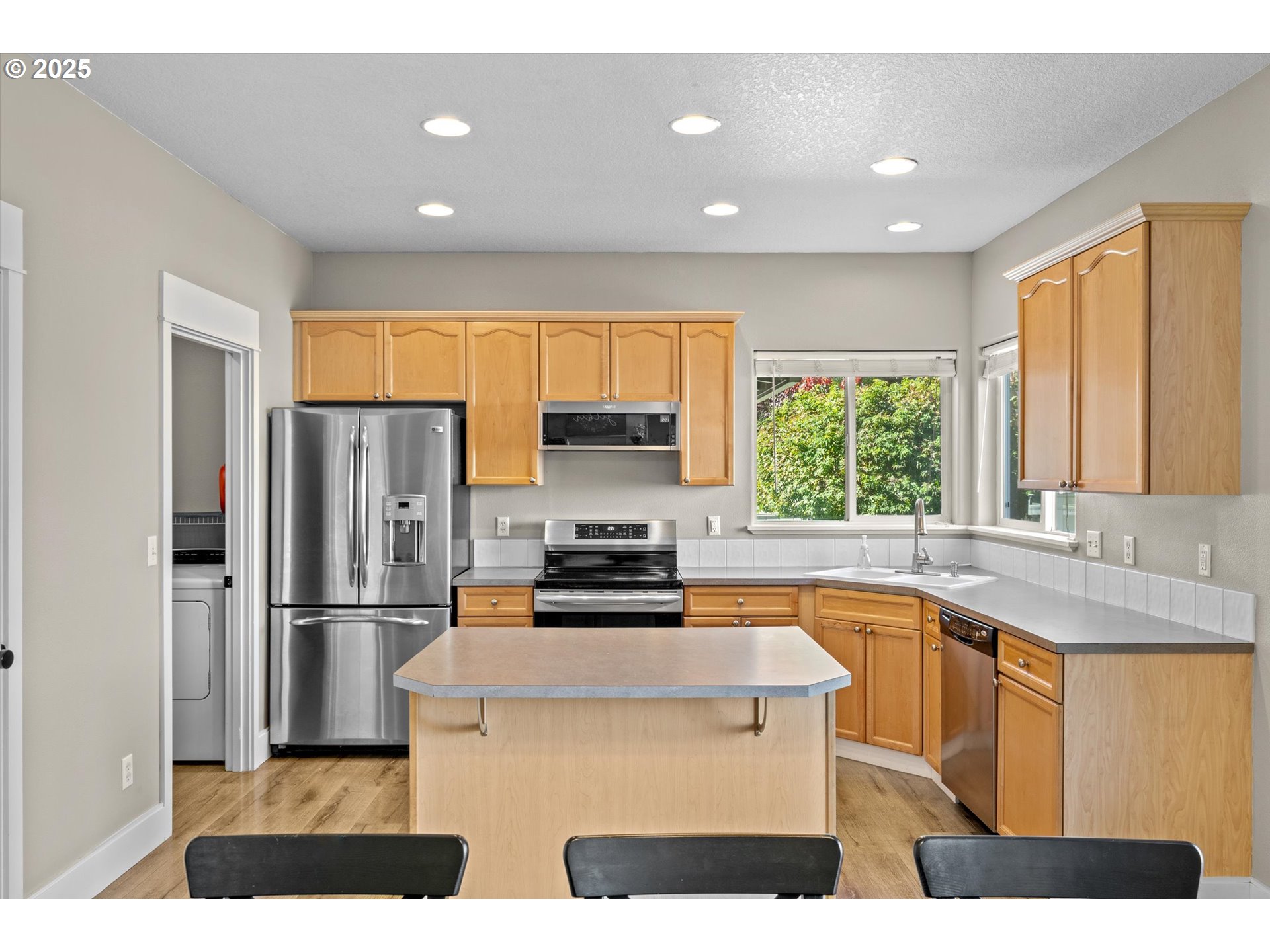 6475 Southeast 33rd Way Gresham, OR 97080 - Photo 14 of 47 a kitchen with stainless steel appliances a refrigerator a sink a stove a microwave a center island and a window