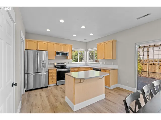 a kitchen with a refrigerator a stove top oven a sink dishwasher and white cabinets with wooden floor