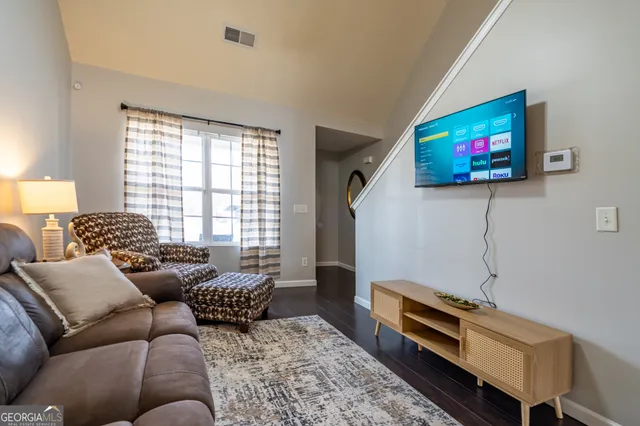 a living room with furniture a flat screen tv and a window