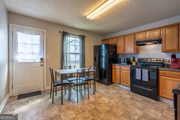 a kitchen with stainless steel appliances kitchen island granite countertop a stove a sink a refrigerator dining table and chairs