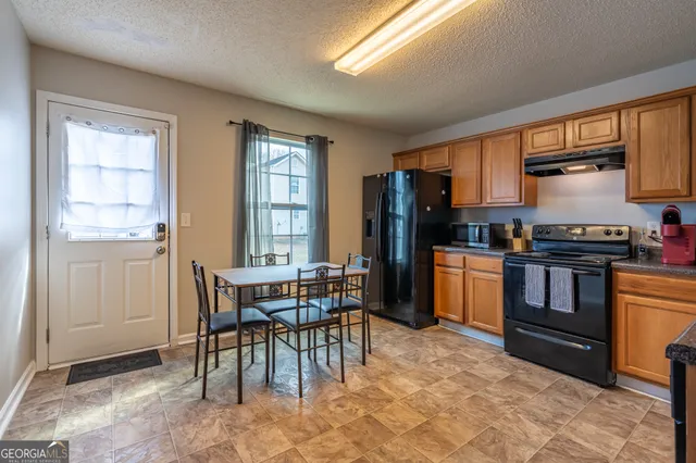 a kitchen with stainless steel appliances kitchen island granite countertop a stove a sink a refrigerator dining table and chairs