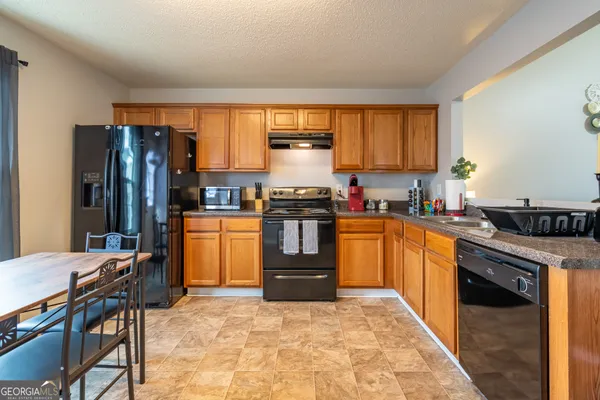 a kitchen with granite countertop a refrigerator stove top oven dining table and chairs