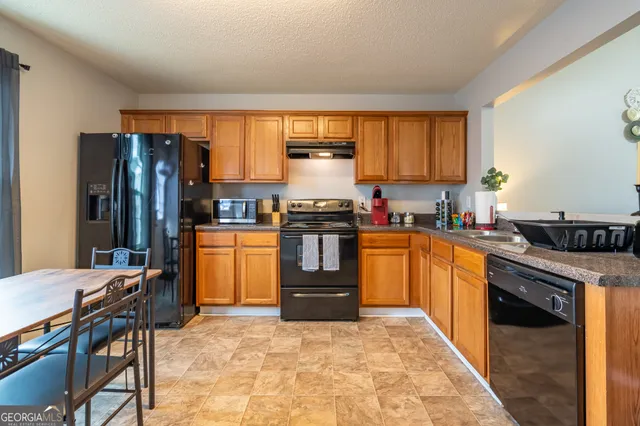 a kitchen with granite countertop a refrigerator stove top oven dining table and chairs