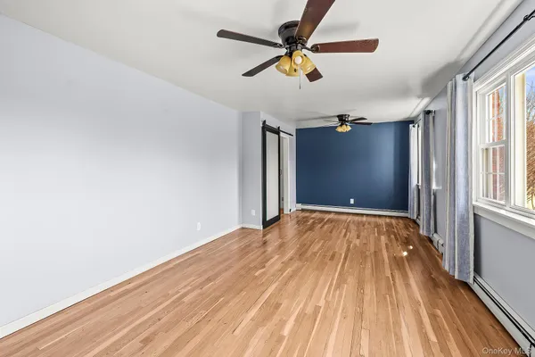 a view of empty room with wooden floor and fan