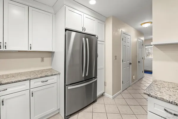 a kitchen with white cabinets and refrigerator