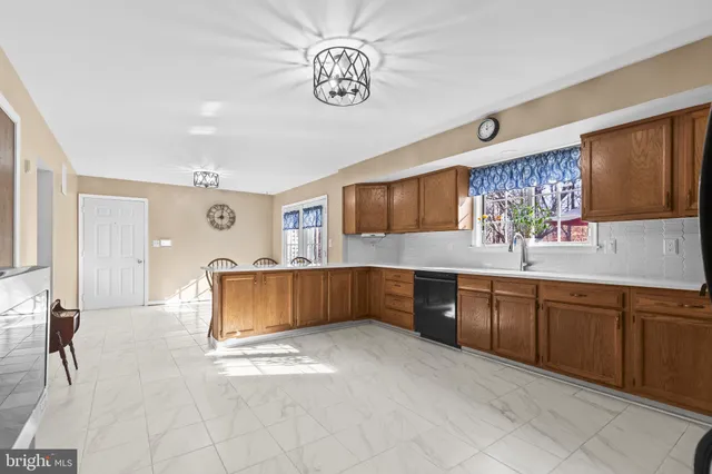 a kitchen with stainless steel appliances granite countertop a refrigerator a sink dishwasher a dining table and chairs with wooden floor